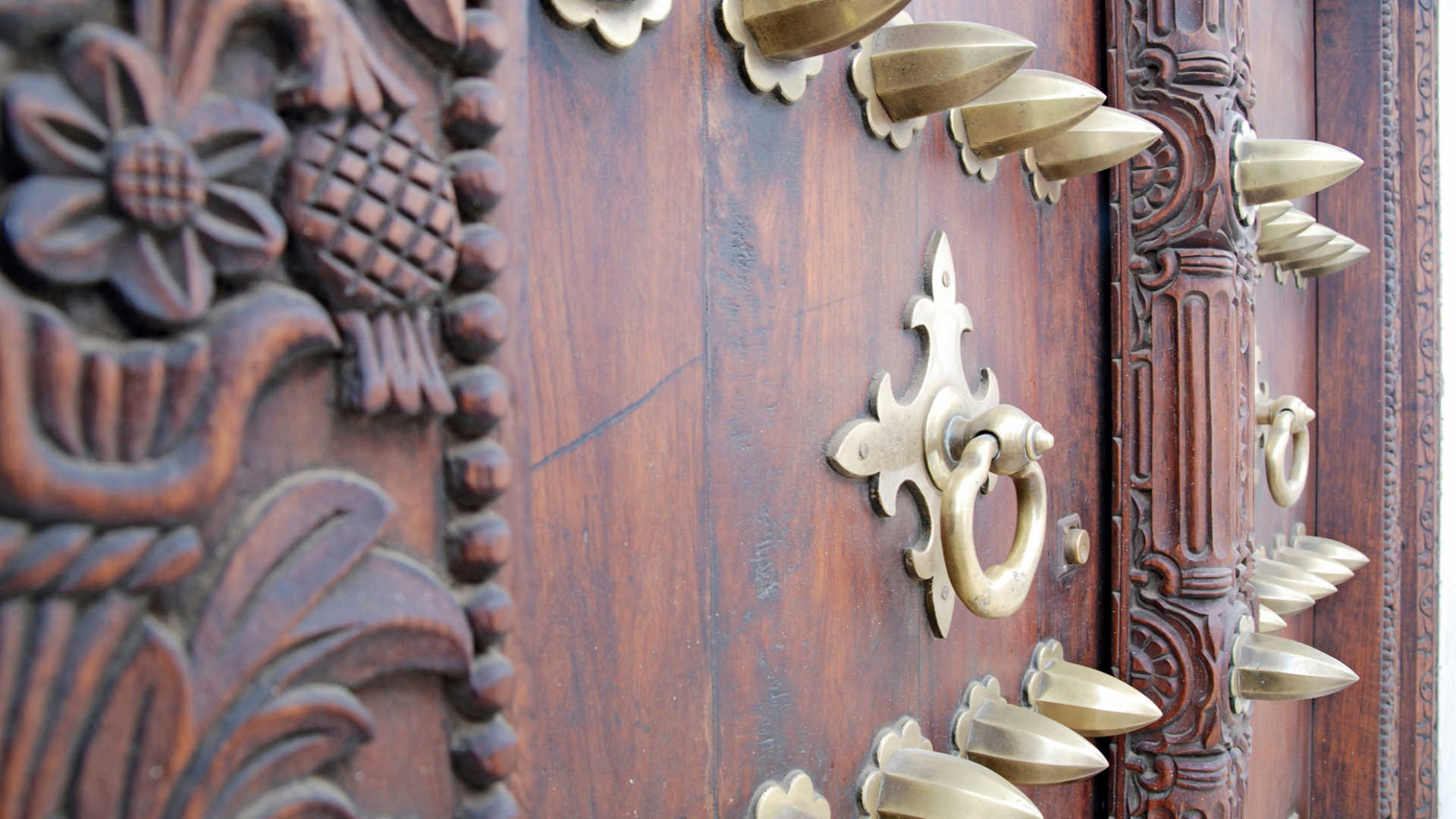 Iconic ornately carved wooden door of a historic Stone Town building with traditional Zanzibari brass studs and Arabic geometric patterns